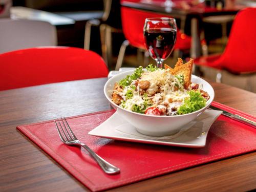 a bowl of salad on a table with a glass of wine at ibis Santiago Estacion Central in Santiago
