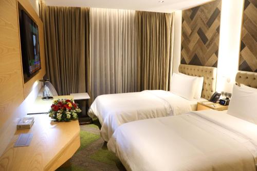 a hotel room with two beds and a television at HANSA- A Premium Residence in Dhaka