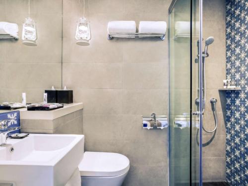 a bathroom with a toilet sink and a shower at Mercure Singapore On Stevens in Singapore