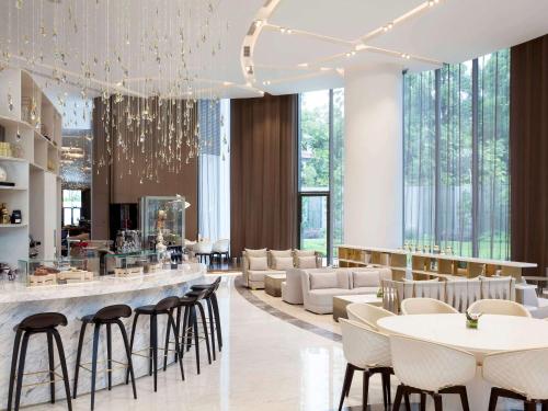 a restaurant with white chairs and a bar with tables at Novotel Singapore On Stevens in Singapore