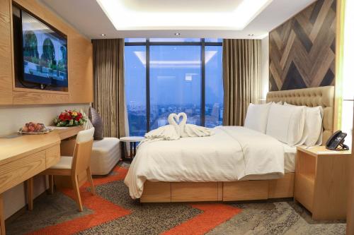 a hotel room with a bed and a desk and a window at HANSA- A Premium Residence in Dhaka