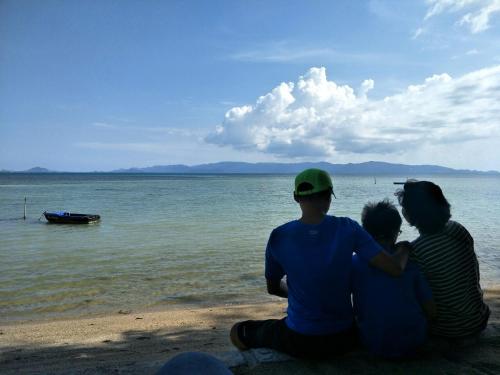 a group of three people sitting on the beach at BeauBo Beach in Baan Tai