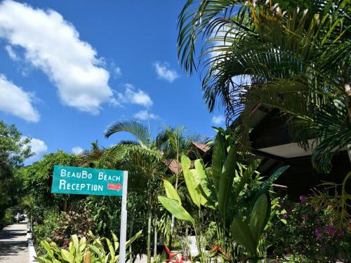 a green street sign in front of a resort at BeauBo Beach in Baan Tai
