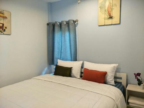 a bedroom with a bed with pillows and a window at BeauBo Beach in Baan Tai