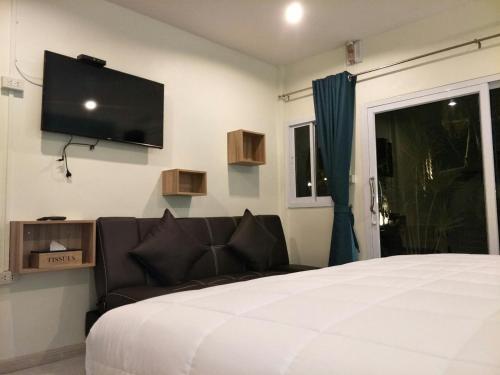 a bedroom with a couch and a flat screen tv on the wall at BeauBo Beach in Baan Tai