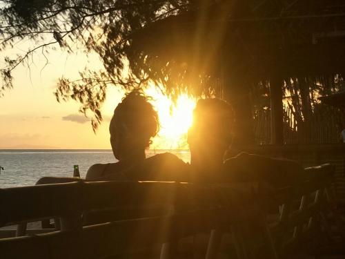 two people sitting on a bench watching the sunset at BeauBo Beach in Baan Tai