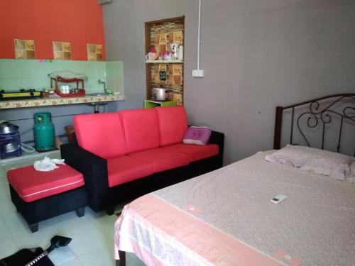 een woonkamer met een rode bank en een bed bij Bonda Guesthouse II in Paka