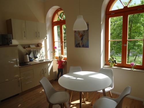 a child standing in a kitchen with a table and chairs at Ferienwohnung Gänseblümchen in Buchholz in Buchholz