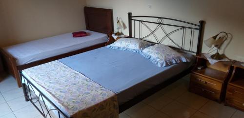 two beds in a bedroom with a dresser and a lamp at Toulatos Pantelis in Pouláta
