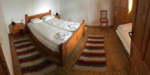 a bedroom with a bed and a rug on a wooden floor at Granny's House in Moisei