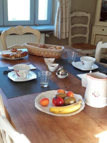 a wooden table with a plate of fruit on it at Maison d'hôtes La Tuilerie in Peschadoires