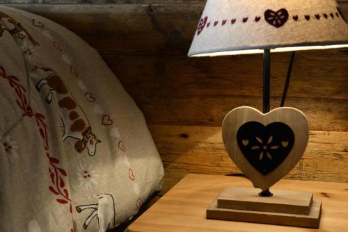 a heart shaped lamp on a table next to a bed at Vieilles Maisons D'Introd in Introd