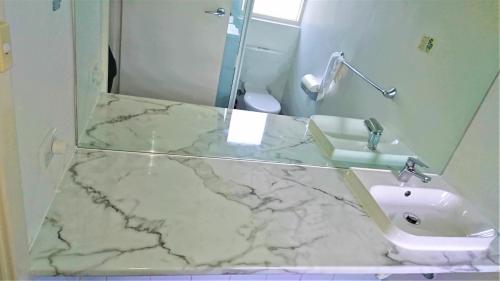 a bathroom with a marble counter top and a sink at Glenelg beach gateway Studio Apartment in Glenelg
