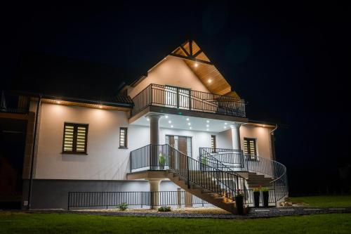 a house with a staircase on the side at night at Willa Kormoran - Pokoje i Apartamenty in Mikołajki
