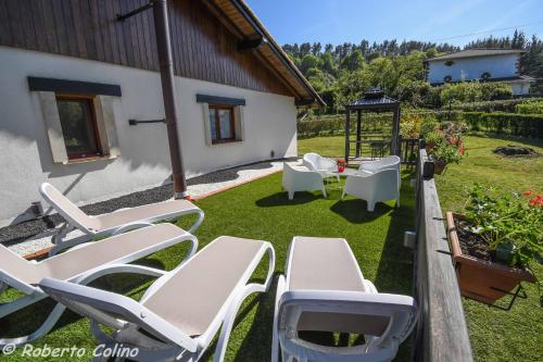 a group of white chairs and tables in a yard at Artesoro Baserria in San Pedro de Galdames