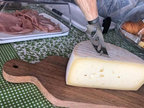 a block of cheese on a cutting board with a knife at Lanterna Room&Breakfast in Carpi