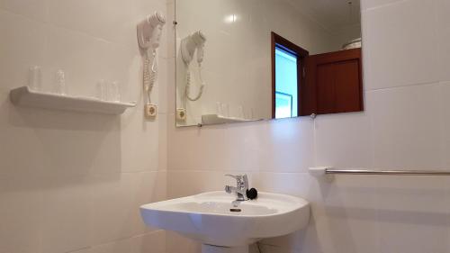 a white bathroom with a sink and a mirror at Hotel Montemar in Noja
