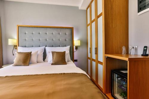 a bedroom with a large bed and a wooden cabinet at Hotel Lusso Mare by Aycon in Budva