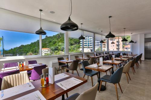 a restaurant with tables and chairs and large windows at Hotel Lusso Mare by Aycon in Budva