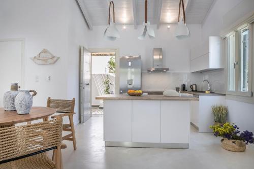 a kitchen with white cabinets and a table and chairs at Olvio Living by the Sea in Sami