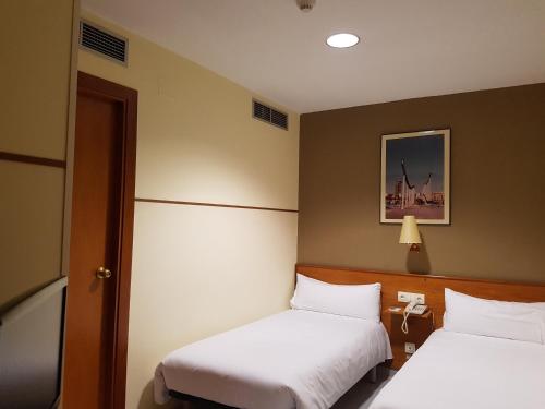 a hotel room with two beds and a picture on the wall at El Jardi in Barcelona