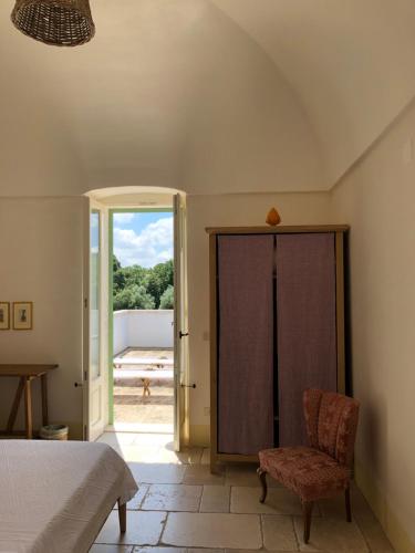 a bedroom with a bed and a chair and a sliding glass door at Masseria Fenicia in Monopoli
