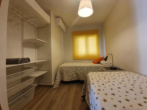 マラガにあるGálvez Flat, at principal railway station in Málagaのベッド2台とクローゼットが備わる小さな客室です。
