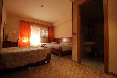 a hotel room with two beds and a window at Hotel Oasi Dei Discepoli in Orvieto