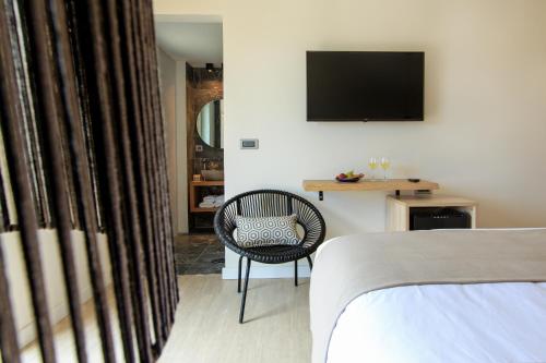 a bedroom with a chair and a television on a wall at 180 South Seaside Hotel in Thermisia