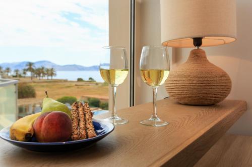 a table with two glasses of wine and a plate of fruit at 180 South Seaside Hotel in Thermisia
