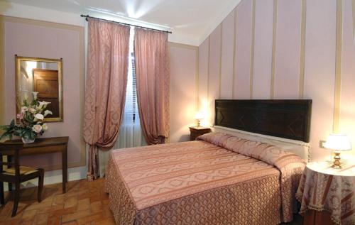 a bedroom with a bed and a table and a window at Antica Sosta in San Quirico dʼOrcia