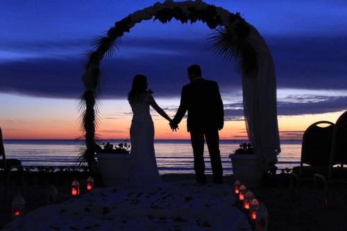 a bride and groom standing under a wedding arch on the beach at Adriatik Hotel, BW Premier Collection in Durrës