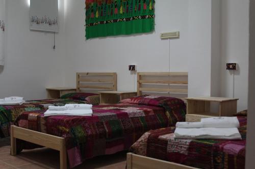 a room with three beds with towels on them at Beteyà Hostel Don Bosco in Catania
