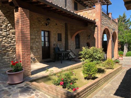 a brick house with a patio with a table and flowers at Agriturismo Casale Giulia in Volterra