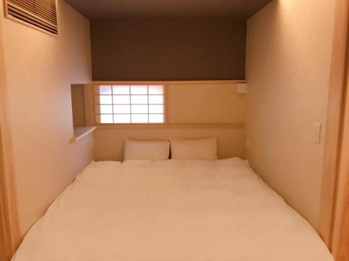 een bed in een kleine kamer met een raam bij 四季々々ぽんと先斗町の京町家 in Kyoto