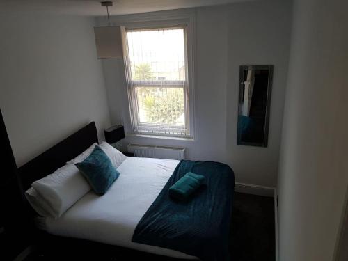 Un dormitorio con una cama con almohadas azules y una ventana en Heart of Southsea,near common and sea., en Portsmouth