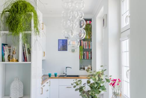 una cucina con pareti bianche, lavandino e lampadario a braccio di Hello Apartments Chlebnicka a Danzica