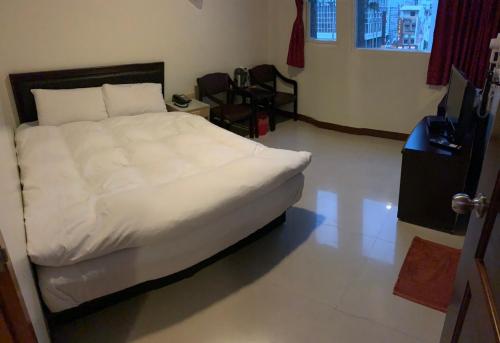 a bedroom with a white bed and a desk at Tang Tsai City Hot Spring Hotel in Jiaoxi