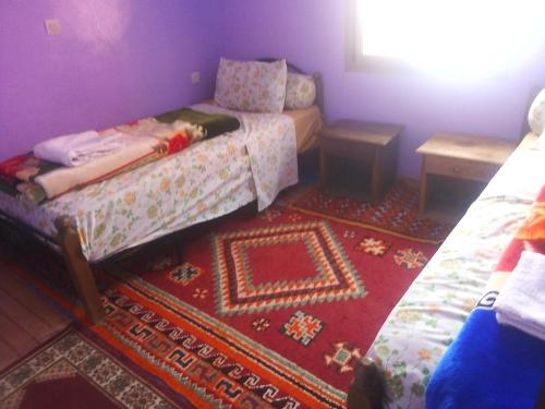 Habitación pequeña con cama y alfombra. en Hotel la belle vue 2100m en Taroudant