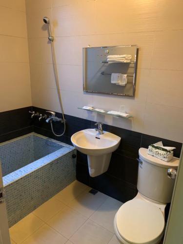 a bathroom with a toilet and a sink and a tub at Tang Tsai City Hot Spring Hotel in Jiaoxi