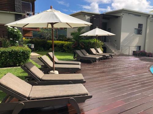 a group of lounge chairs and an umbrella on a deck at Beach Apartment - Trou aux Biches - Ground Floor in Mont Choisy