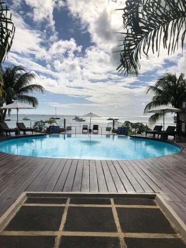 a swimming pool with chairs and umbrellas on a wooden deck at Beach Apartment - Trou aux Biches - Ground Floor in Mont Choisy