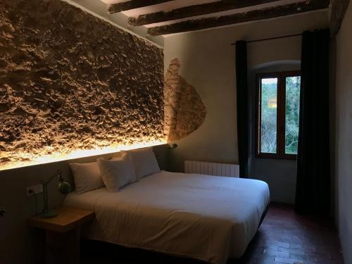 1 dormitorio con cama blanca y ventana en Hostal de Bianya, en Vall de Bianya