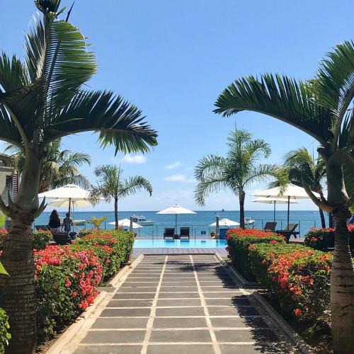 a resort with a swimming pool and palm trees and the ocean at Beach Apartment - Trou aux Biches - Ground Floor in Mont Choisy