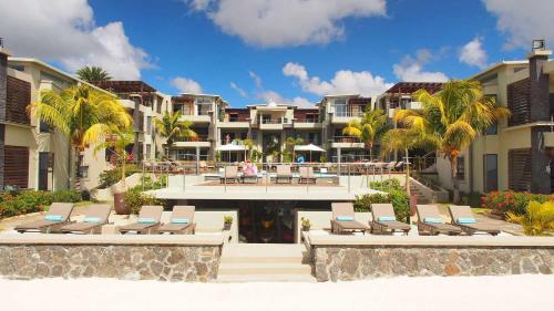 a resort with lounge chairs and palm trees and buildings at Beach Apartment - Trou aux Biches - Ground Floor in Mont Choisy