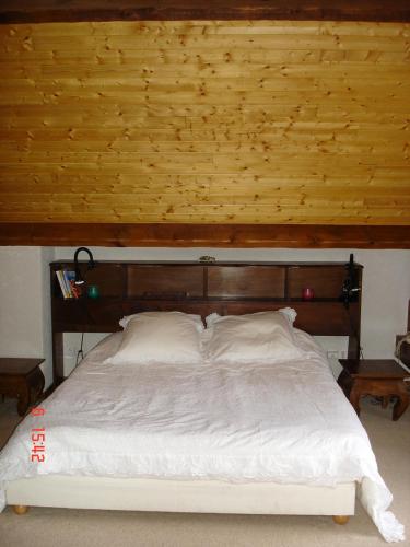 a bedroom with a large bed with a wooden headboard at gîte Vallée des Nestes in Bareilles