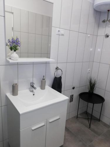 a white bathroom with a sink and a mirror at APARTMANI NOVA in Živogošće