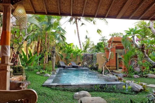 a swimming pool in the middle of a garden at Honeymoon Green Villa in Ubud