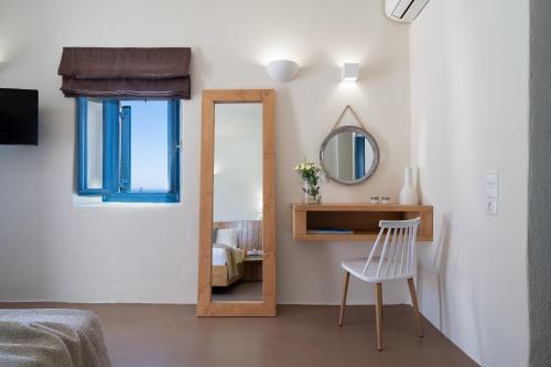 a mirror in a room with a chair and a bed at Nalas Suites in Emporio Santorini