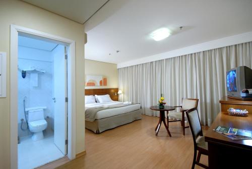 a hotel room with a bed and a desk and a table at Luz Plaza São Paulo in Sao Paulo